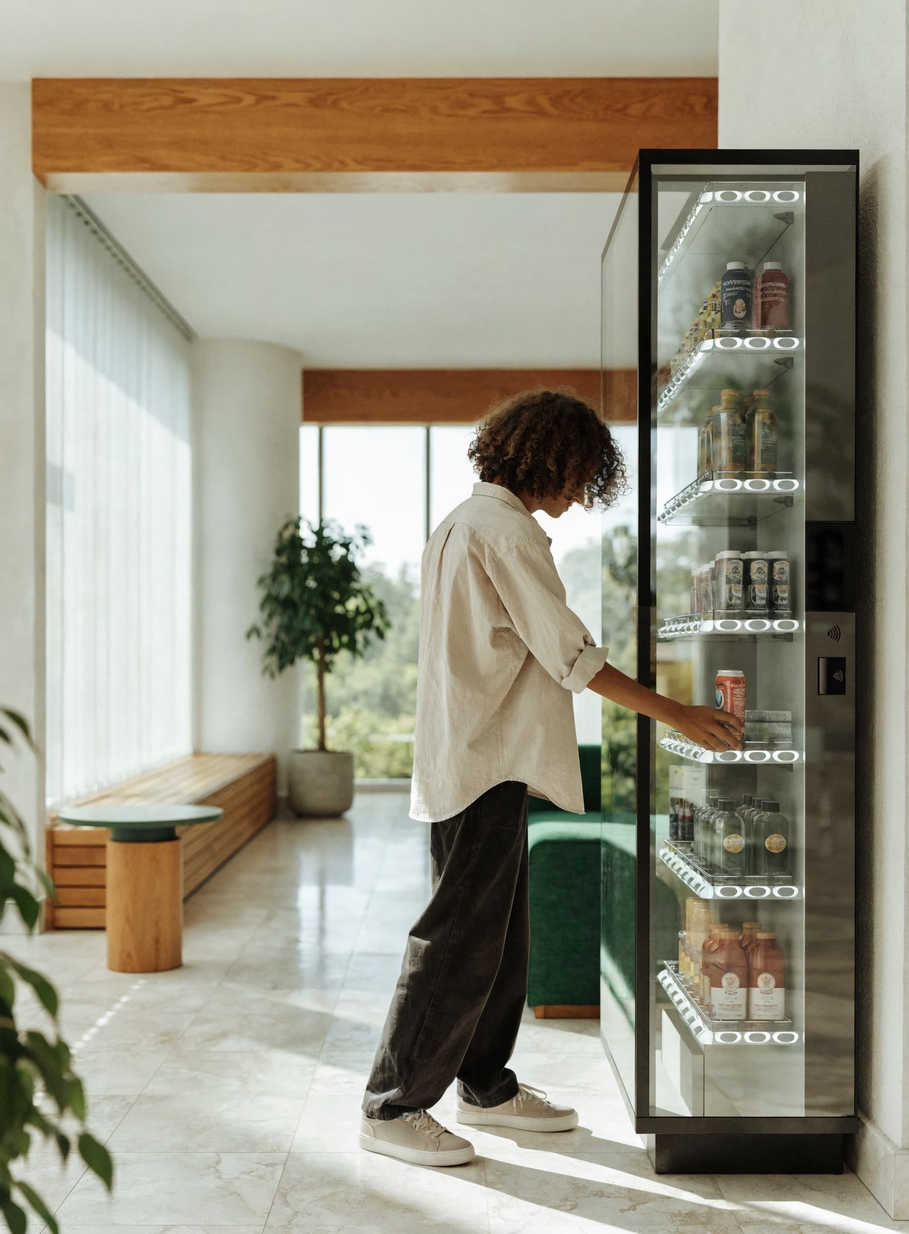 A resident grabbing a cold drink from a modern Quickstop smart vending micromarket in a bright apartment lobby